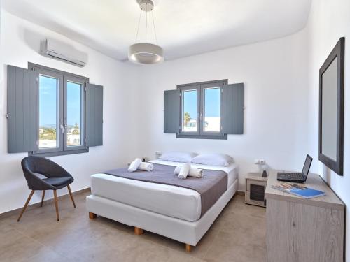 a bedroom with a bed and a chair and windows at Mouragio Stay - Aliki , Paros in Aliki