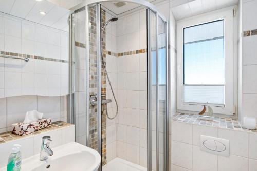 a white bathroom with a shower and a sink at Apartment Korthals 41 in Wangerland