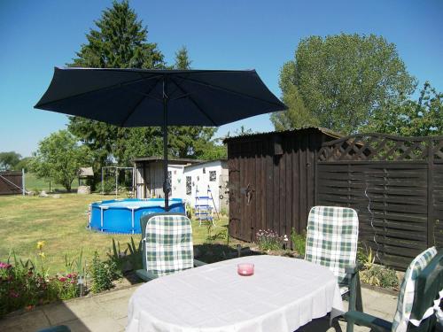 a table and chairs with an umbrella in a yard at Reethaus Natalie in Korswandt