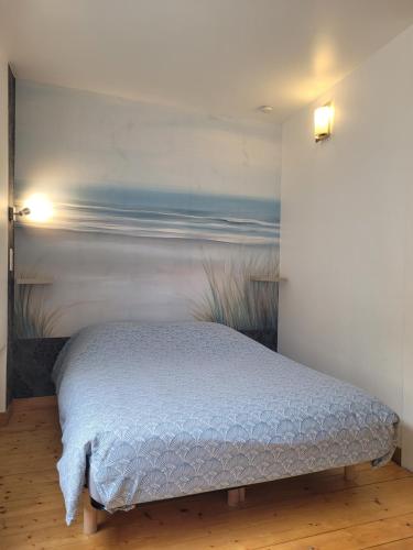 a bed in a room with a painting on the wall at Avec CLIMATISEUR appartement DESIGN vous propose, un appartement 2 chambres et salon, 3 appartements une pièce, NETFLIX, lits faits à votre arrivée, serviettes de toilette, Ménage, Wifi ,Plage à 190m, BOX à Vélos, paiement 3 fois sans frais in Dieppe