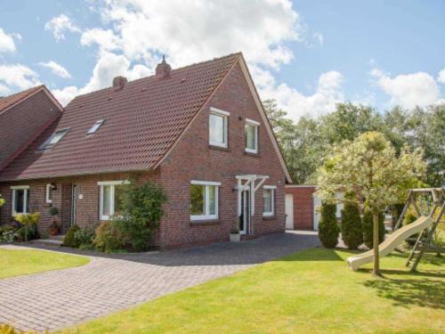 a brick house with a playground in the yard at Birgits Huuske in Stedesdorf