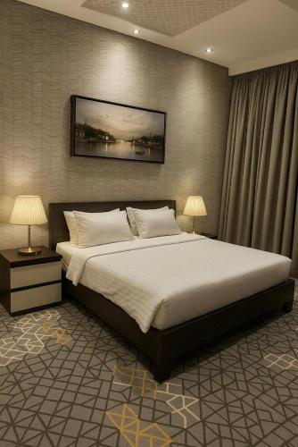 a bedroom with a large bed and two lamps at شقق الشرفة للشقق المفروشة -AlSHORFA FURNISHED APARTMENT in Riyadh