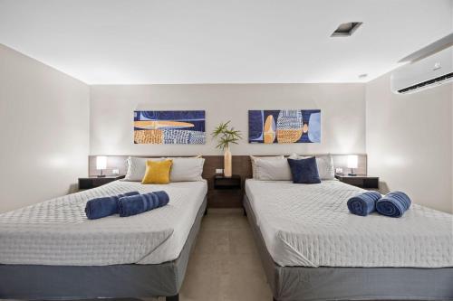 two beds in a room with blue pillows on them at Ocean Breeze in San Juan