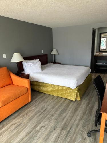 a bedroom with a bed and an orange couch at Home Town Inn in Flint