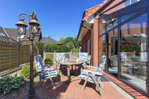 a patio with a table and chairs and a street light at Ferienhaeuser Deichkrone in Bensersiel
