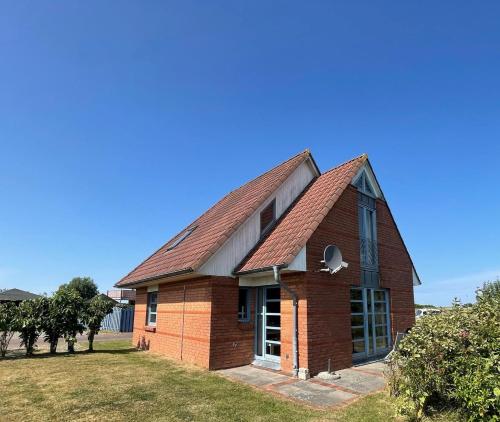 a red brick house with a roof at Ferienhaus Rieke in Friedrichskoog-Spitze