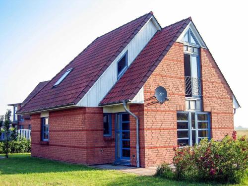a small brick house with a red roof at Ferienhaus Rieke in Friedrichskoog-Spitze