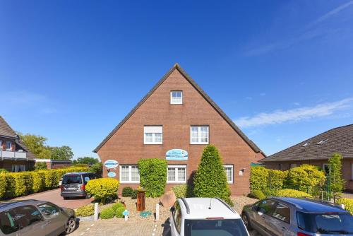 a brick house with cars parked in front of it at Haus Nordseesterne in Bensersiel