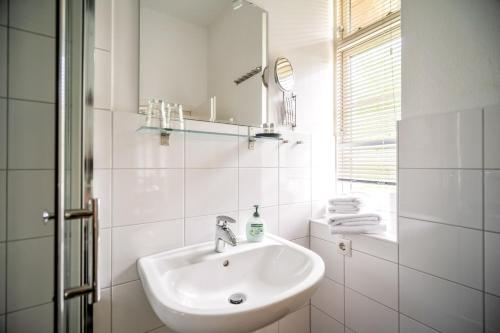 ein weißes Badezimmer mit Waschbecken und Spiegel in der Unterkunft Weizenkammer in Rechlin