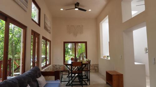 a living room with a table and chairs and windows at Casa Mayali - Walk to Lagoon in Bacalar