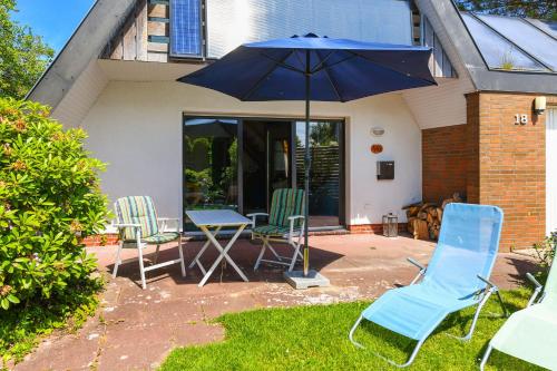 a patio with three chairs and a table and an umbrella at Ferienhaus Leevje in Neuharlingersiel