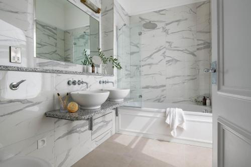 a white bathroom with two sinks and a tub at The Headland Hotel and Spa in Newquay