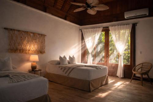 a bedroom with two beds and a window and a fan at Villa Alda Bávaro in Punta Cana