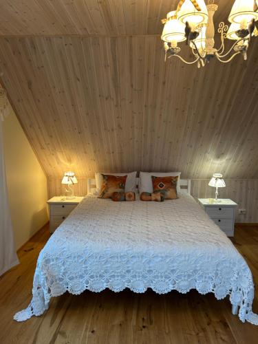 ein Schlafzimmer mit einem weißen Bett und zwei Nachttischen in der Unterkunft Muhu Kulla Saadu puhkemaja mere ääres in Raugi
