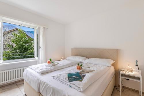 a bedroom with a bed with white sheets and a window at Residenza La Serenata in Cavigliano