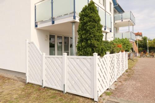 a white fence in front of a house at Ferienwohnung Maigloeckchen 05 str in Karlshagen
