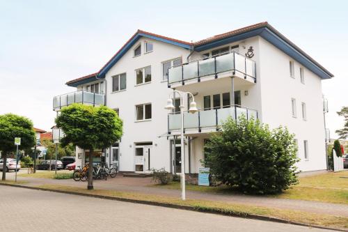 a white building with balconies on the side of a street at Ferienwohnung Maigloeckchen 05 str in Karlshagen