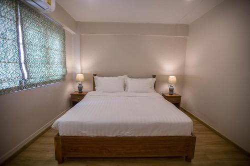 a bedroom with a white bed with two lamps on tables at Vera Nidhra - Self check-in after 6pm in Bangkok