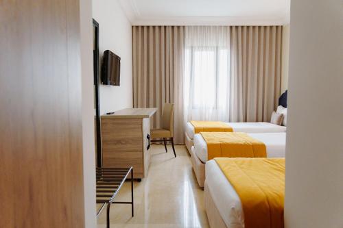 a hotel room with three beds and a dresser at hôtel LE PACHA in Tunis