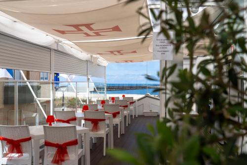 a row of white tables and chairs with red bows at House Barra Beach in Praia da Barra