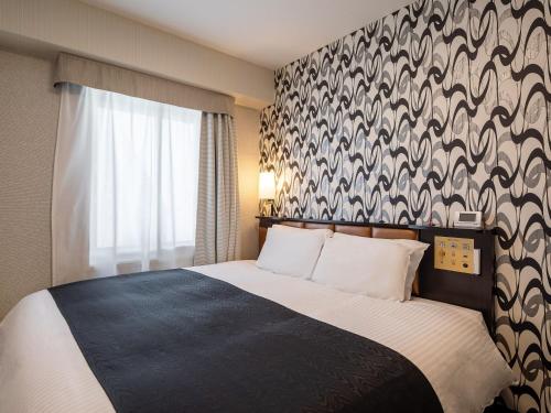 a hotel room with a bed and a window at APA Hotel Sapporo Odori Ekimae Minami in Sapporo