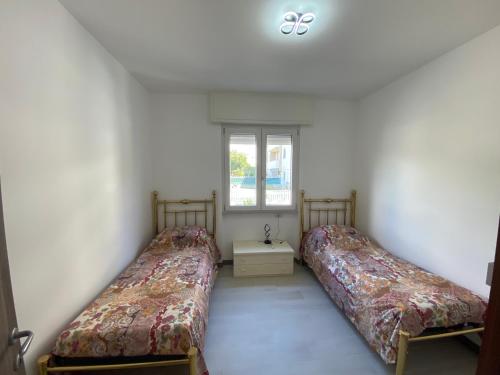 two beds in a room with a window at Rifugio del Mare con piscina e palestra in Loano