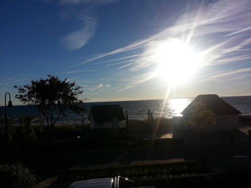 a sun is shining over the ocean on a clear day at Strandhaus Buchtmitte in Haffkrug