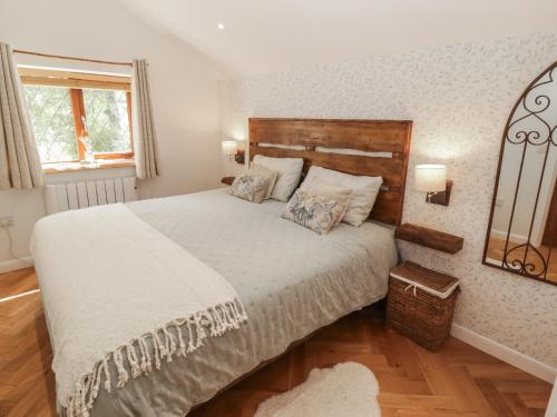 a bedroom with a large bed and a mirror at Cân yr adar in Bridgend