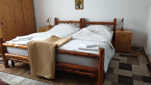 a wooden bed with white sheets and towels on it at Pensiunea Iris in Săcele