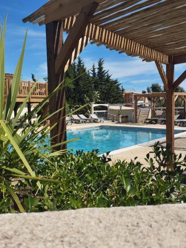 a swimming pool with a wooden pergola next to a resort at Camping les Acacias in Fréjus