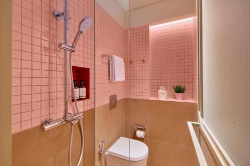 a pink tiled bathroom with a shower and a toilet at lyf Chinatown Singapore in Singapore