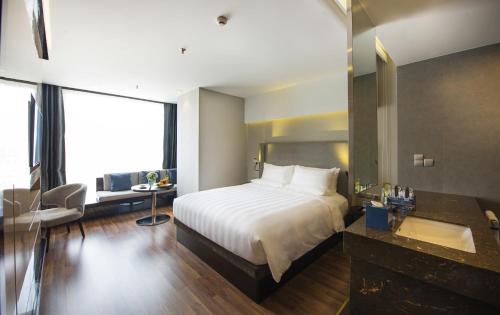 a bedroom with a bed and a bathroom with a sink at Novotel Suites Hanoi in Hanoi