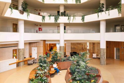 a lobby with plants and people sitting in a building at Falésia Hotel - Adults Only in Albufeira