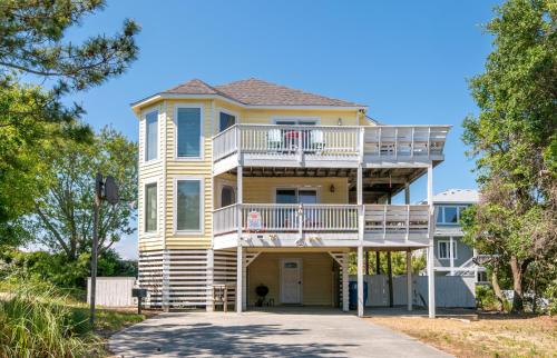 a large yellow house with a balcony and stairs at Shore is Fun - Duck, Poteskeet, Beach 480 Yds, 3 Min. Walk to Downtown, Pool, Hot Tub, YR Flex in Duck
