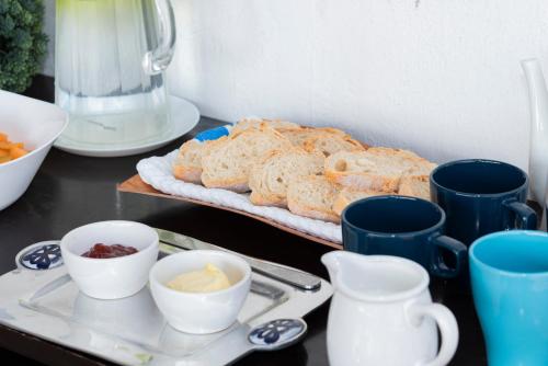a table with a tray of bread and blue cups at Hostal Nube Mia Guadalajara in Guadalajara