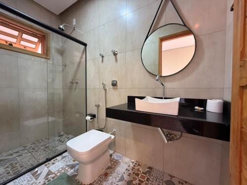 a bathroom with a toilet and a mirror at Pousada Carraro in Delfinópolis