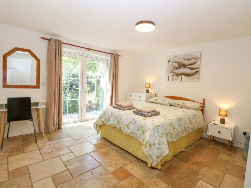 a bedroom with a bed and a desk and a window at Mill Lodge in Brisley