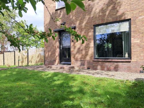 a brick house with a window and a grass yard at B&B De Zeeaster in Kimswerd
