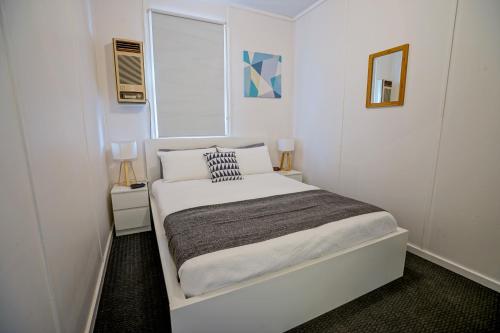 a small white bedroom with a bed and a window at Breakaway Moonta Bay in Port Moonta