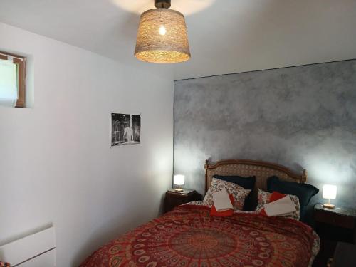 a bedroom with a bed with a red bedspread and two lamps at Gite Le Romanesque in Clelles