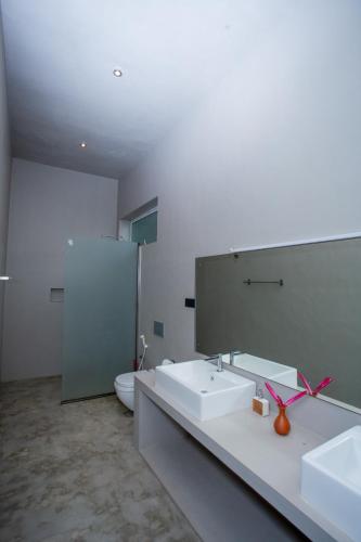 a bathroom with two sinks and a mirror and a toilet at Sudu Appu Villa Beruwala in Beruwala