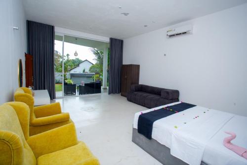 a bedroom with a large bed and two yellow chairs at Sudu Appu Villa Beruwala in Beruwala