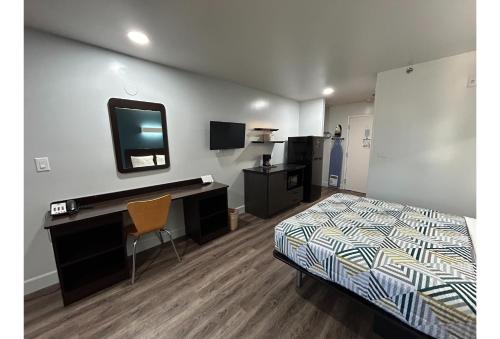 a bedroom with a bed and a desk and a tv at Studio 6 Suites Hesperia CA West Main Street I 15 in Hesperia