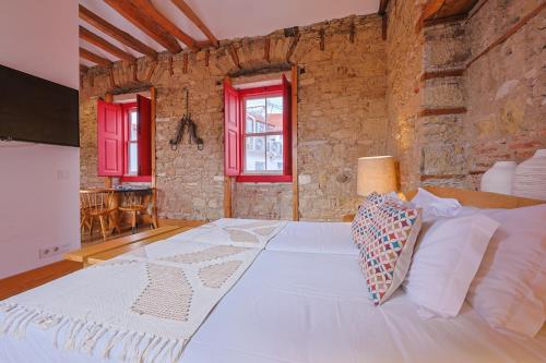 a large white bed in a room with red windows at Casa da Sé by PURUS in Coimbra
