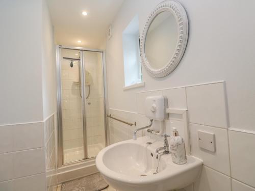 a white bathroom with a sink and a shower at Mini Mena in St Austell