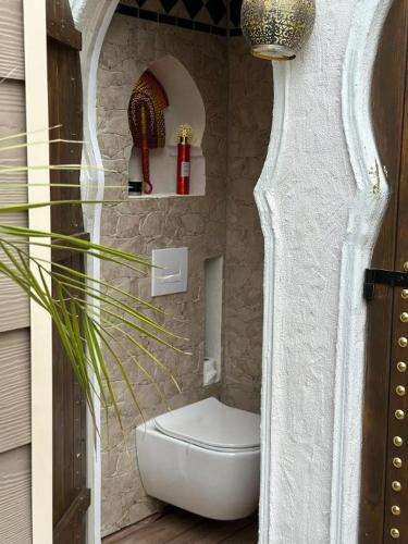 a bathroom with a toilet in a stone wall at Lodge SAHARA in Arques