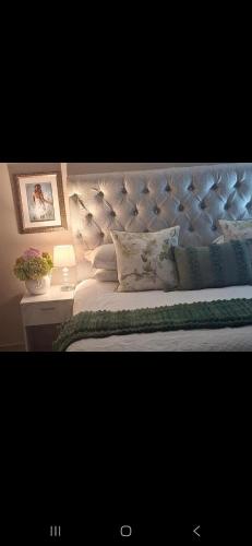 a bed with a tufted headboard and a side table with a lamp at Kaleb Guesthouse in Bethlehem