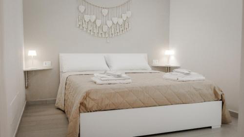 a white bedroom with a bed with two towels on it at Maison La Chicca in Molfetta