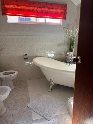 a bathroom with a tub and a toilet and a window at Touchdown Villa in Pointe Larue