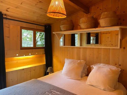 a bedroom with a bed with two pillows and a lamp at Cabane du Bertic in Lège-Cap-Ferret